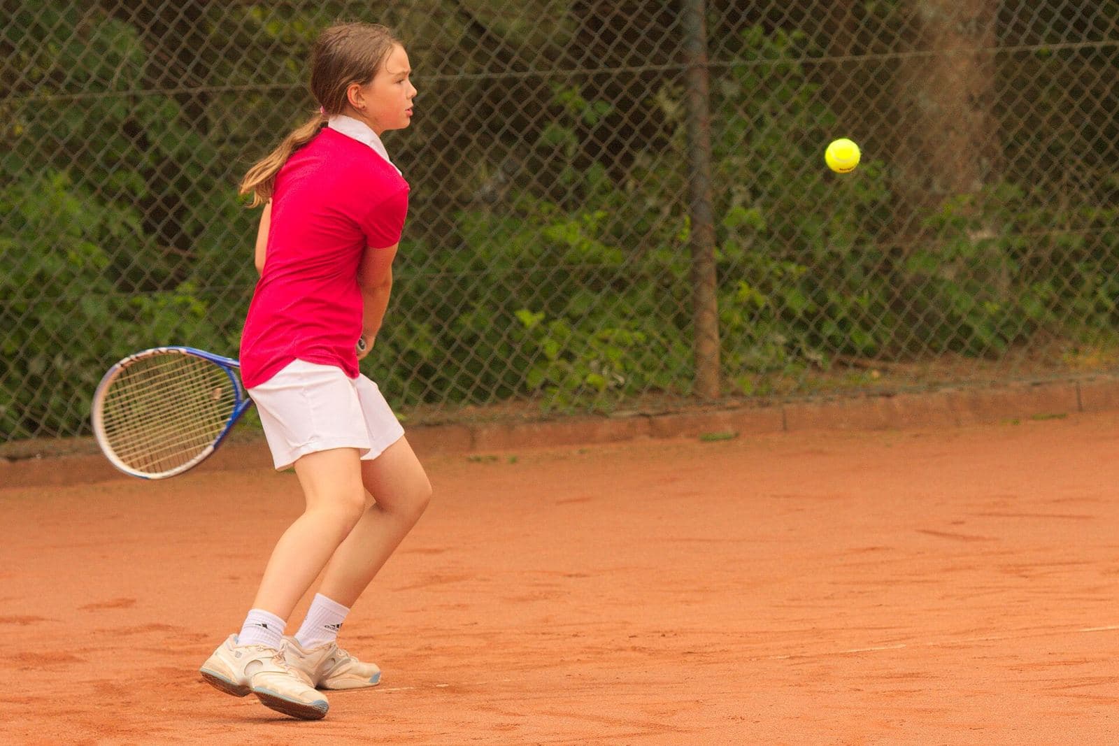 A young player turning for a forehand on a clay court